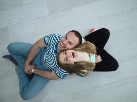 top view of Cheerful young couple sitting with back to each other on floor