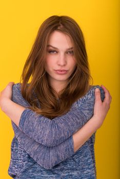 Portrait of a beautiful positive young woman while playing with her long silky hair isolated on yellow background