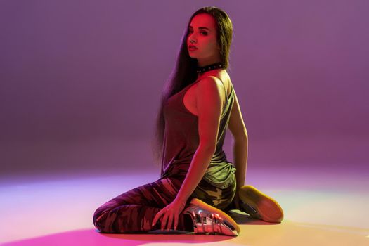 Attractive young blonde woman in the studio dancing Booty dance on a pink background. Color filters