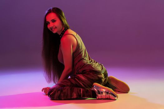 Attractive young blonde woman in the studio dancing Booty dance on a pink background. Color filters