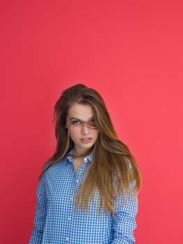 Portrait of a beautiful positive young woman while playing with her long silky hair isolated on red background