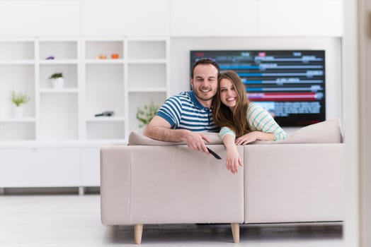Young couple on the sofa watching television together in their luxury home