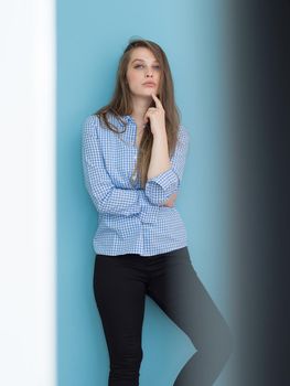 Portrait of a beautiful positive young woman while playing with her long silky hair isolated on blue background