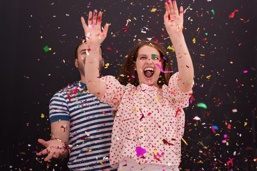 handsome young couple celebrating new year and chrismas party while blowing confetti decorations to camera isolated over gray background