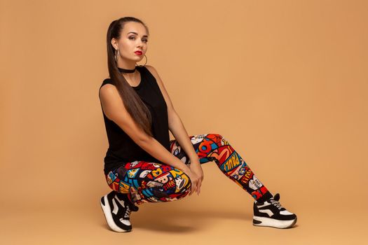 Young female dancer on studio background. Young modern style dancer girl sitting on floor in studio. Pretty female dancer of dancehall, jazz funk, hip hop