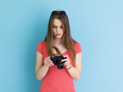 portrait of a smiling pretty girl taking photo on a retro camera isolated over blue background