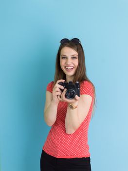 portrait of a smiling pretty girl taking photo on a retro camera isolated over blue background