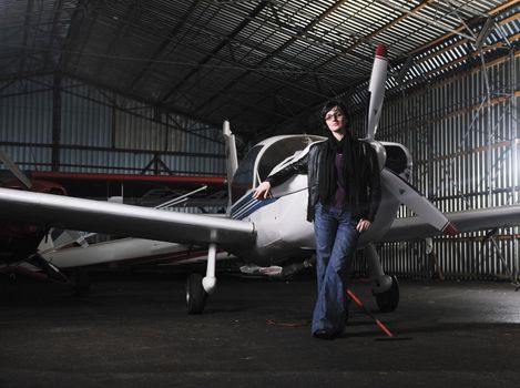beautiful young woman model in fashion clothes posing in front of old private airplane 