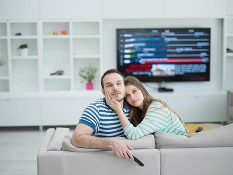 Young couple on the sofa watching television together in their luxury home