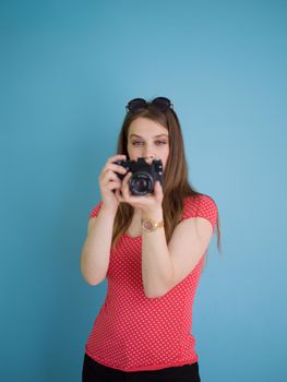 portrait of a smiling pretty girl taking photo on a retro camera isolated over blue background