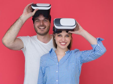 happy young couple getting experience using VR-headset glasses of virtual reality isolated over red background