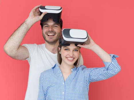 happy young couple getting experience using VR-headset glasses of virtual reality isolated over red background