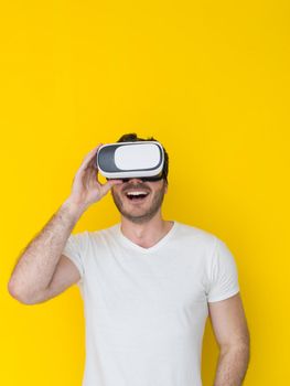 Happy man getting experience using VR headset glasses of virtual reality, isolated on yellow background