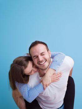 happy young man piggybacking his girlfriend isolated on blue background