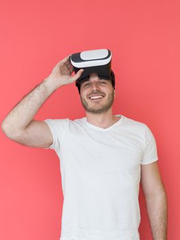 Happy man getting experience using VR headset glasses of virtual reality, isolated on red background