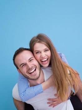 happy young man piggybacking his girlfriend isolated on blue background