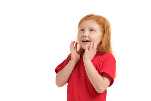 What a surprise. Pleasant cute upbeat little girl holding her hands near face and smiling while expressing joy.