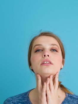 Portrait of a beautiful positive young woman while playing with her long silky hair isolated on blue background