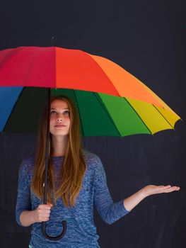 portrait of a young handsome woman with a colorful umbrella isolated on a gray background
