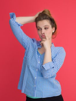 Portrait of a beautiful positive young woman while playing with her long silky hair isolated on red background