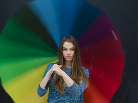 portrait of a young handsome woman with a colorful umbrella isolated on a gray background