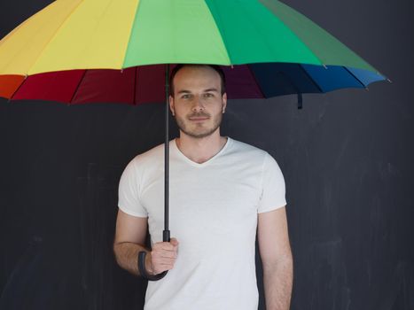 portrait of a young handsome man with a colorful umbrella isolated on a gray background