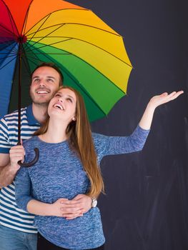 portrait of a beautiful loving young couple with a colorful umbrella isolated on a gray background