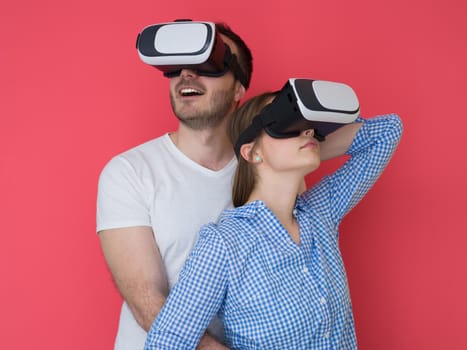 happy young couple getting experience using VR-headset glasses of virtual reality isolated over red background