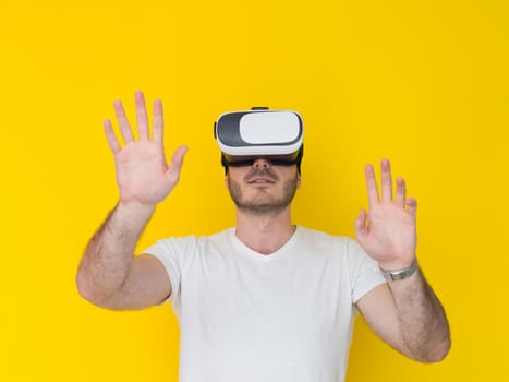 Happy man getting experience using VR headset glasses of virtual reality, isolated on yellow background