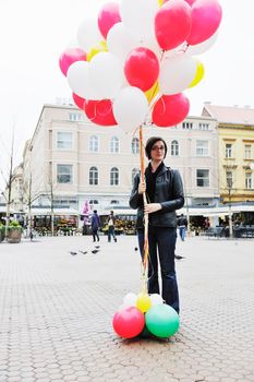 happy young woman holding lots of ballons and try to fly 