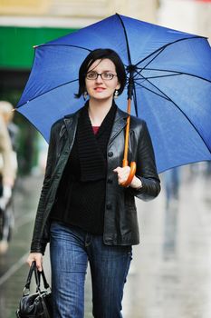 one young happy woman walking in cyti with rainy weater and blue umbrella