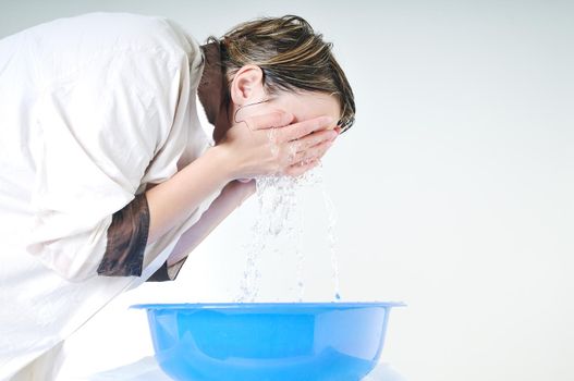 bautiful young woman wash face with clean water isolated on white in studio