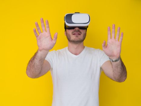 Happy man getting experience using VR headset glasses of virtual reality, isolated on yellow background