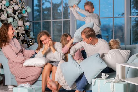 Big Happy family with many kids having fun and pillow fight under the Christmas tree. Christmas family eve, christmas mood concept