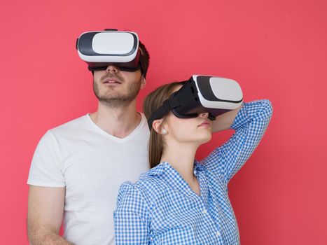 happy young couple getting experience using VR-headset glasses of virtual reality isolated over red background