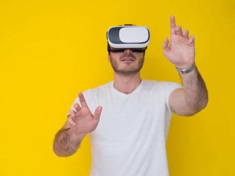 Happy man getting experience using VR headset glasses of virtual reality, isolated on yellow background