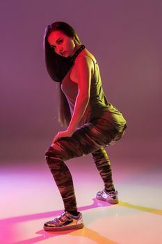 Attractive young blonde woman in the studio dancing Booty dance on a pink background. Color filters