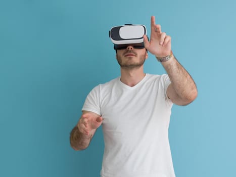 Happy man getting experience using VR headset glasses of virtual reality, isolated on blue background