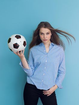 Portrait of a beautiful positive young woman while playing with a soccer ball isolated on blue background