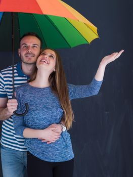 portrait of a beautiful loving young couple with a colorful umbrella isolated on a gray background