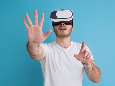 Happy man getting experience using VR headset glasses of virtual reality, isolated on blue background