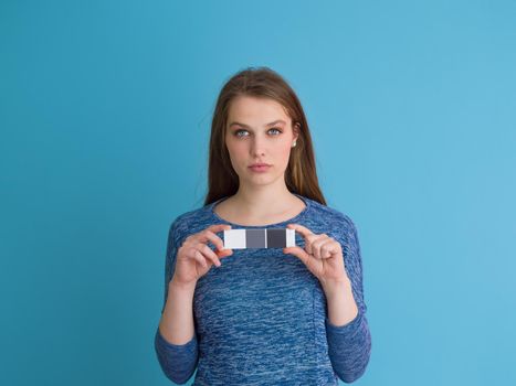 Portrait of a beautiful positive young woman while playing with her long silky hair isolated on blue background