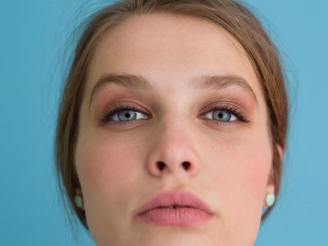 Portrait of a beautiful positive young woman while playing with her long silky hair isolated on blue background