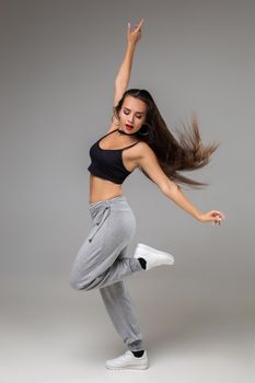 Modern dancer poses in front of the gray studio background. Modern dance styles, dancehall, jazz funk, hip hop
