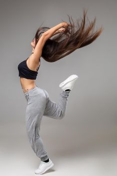Modern dancer poses in front of the gray studio background. Modern dance styles, dancehall, jazz funk, hip hop