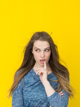 Portrait of a beautiful positive young woman while playing with her long silky hair isolated on yellow background
