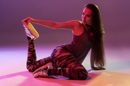 Attractive young blonde woman in the studio dancing Booty dance on a pink background. Color filters