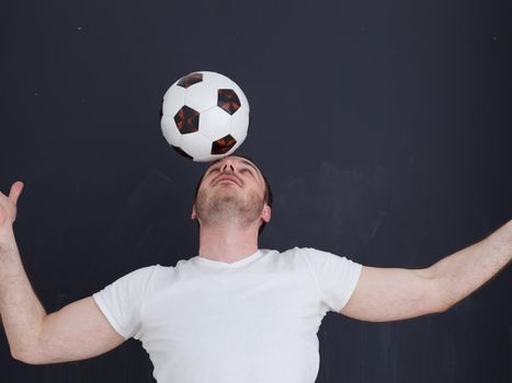 young handsome man playing with soccer ball isolated over grey background