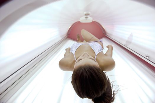 Beautiful young woman have tanning skin treatment in modern solarium