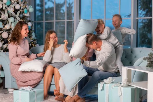 Big Happy family with many kids having fun and pillow fight under the Christmas tree. Christmas family eve, christmas mood concept